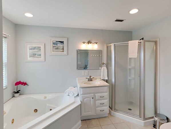 A bathroom with a bathtub, vanity, and walk-in shower.