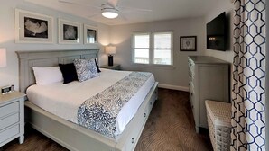 A bedroom with a bed, nightstands, a dresser, a ceiling fan, and a window with blinds.