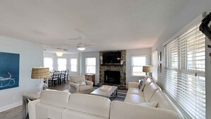 A spacious living room with a sectional sofa, a fireplace, and a dining area with a table and chairs.
