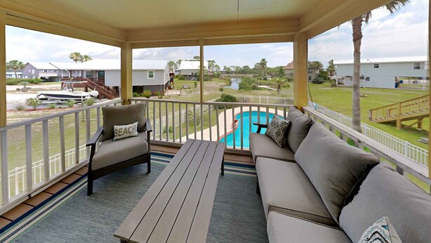 A covered outdoor area with a pool, a sofa, and a table.