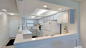 Una cocina moderna con armarios blancos, una isla central y electrodomésticos integrados.