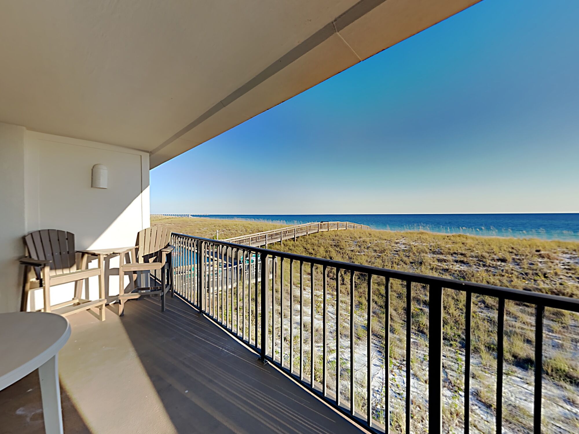 A balcony with a view of the beach and ocean.
