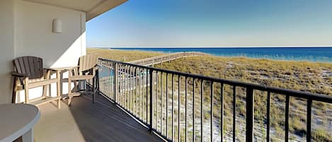 A balcony with a view of the beach and ocean.
