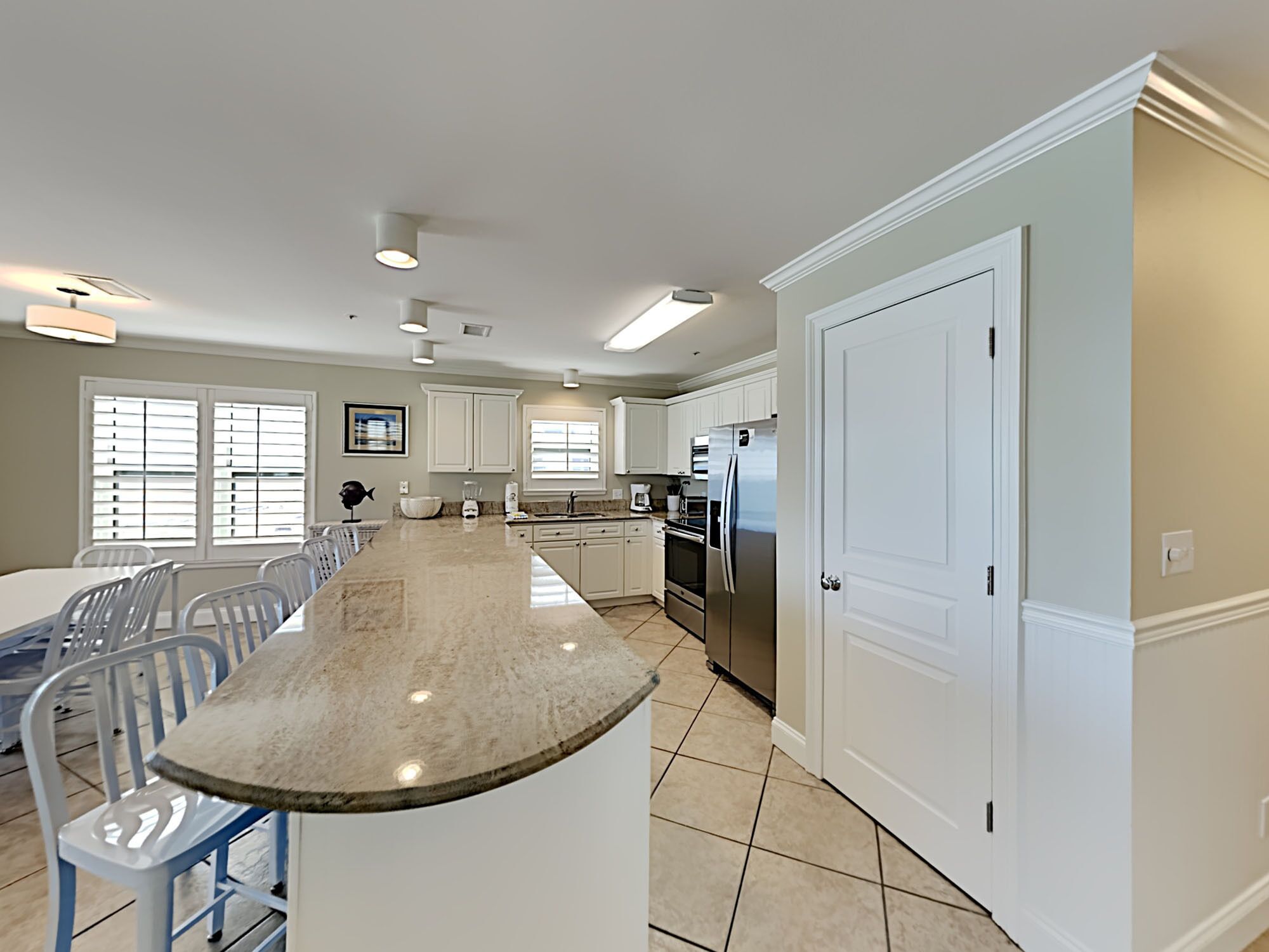 A modern kitchen with white cabinets, a large island, and stainless steel appliances.