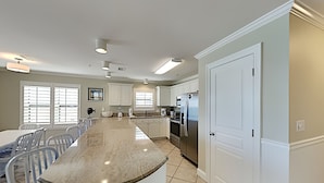 A modern kitchen with white cabinets, a large island, and stainless steel appliances. - Emerald Dunes #405 by Southern Vacation Rentals (Destin)