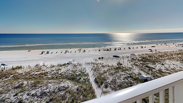 A beach with people, umbrellas, and a fence. - Emerald Dunes #405 by Southern Vacation Rentals (Destin)