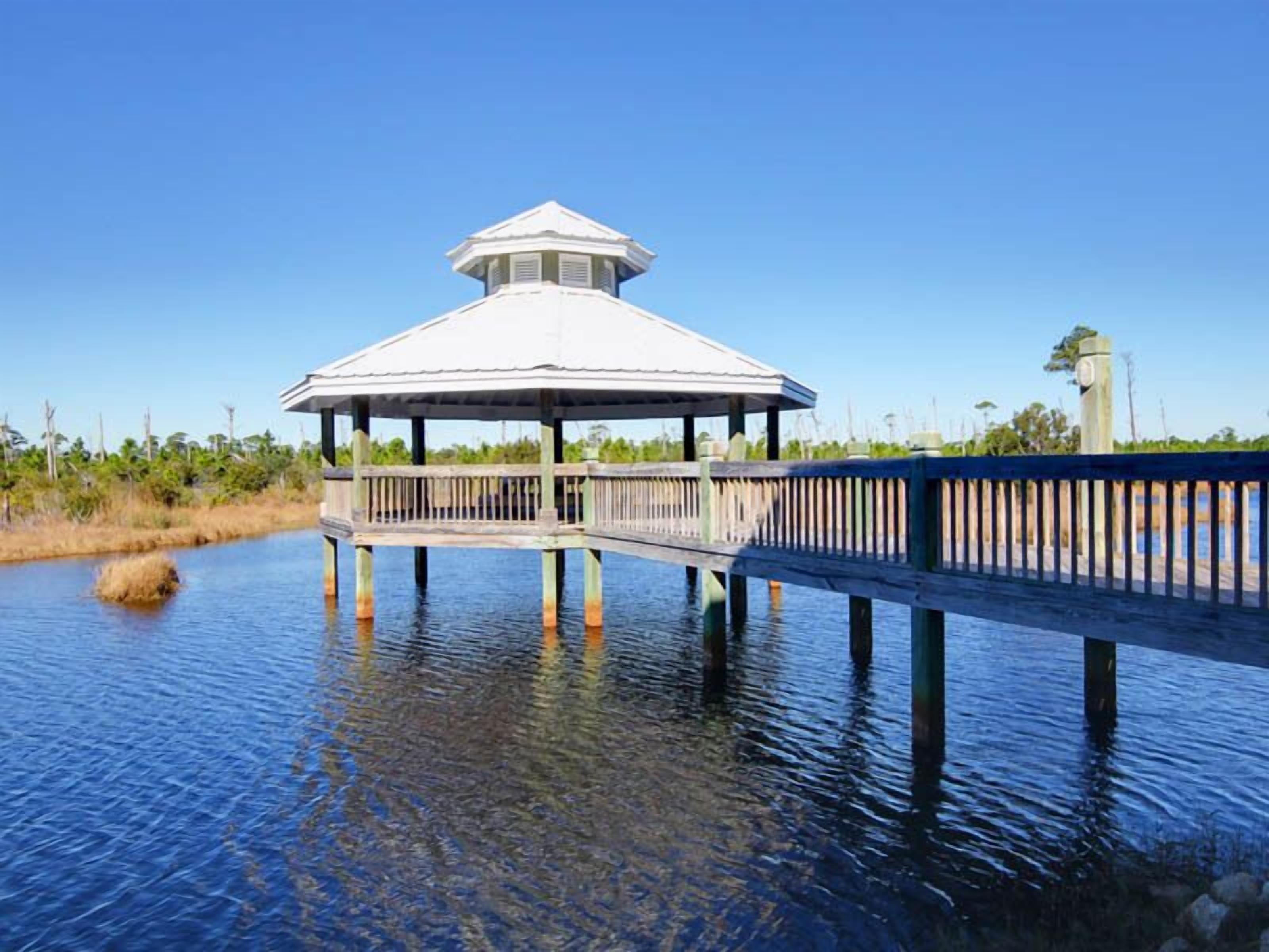 A gazebo with a hexagonal roof and a wooden deck extending over water.