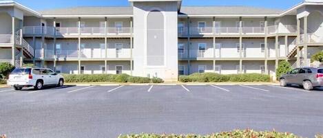 A multi-story motel with a central entrance, parking lot, and a row of balconies.