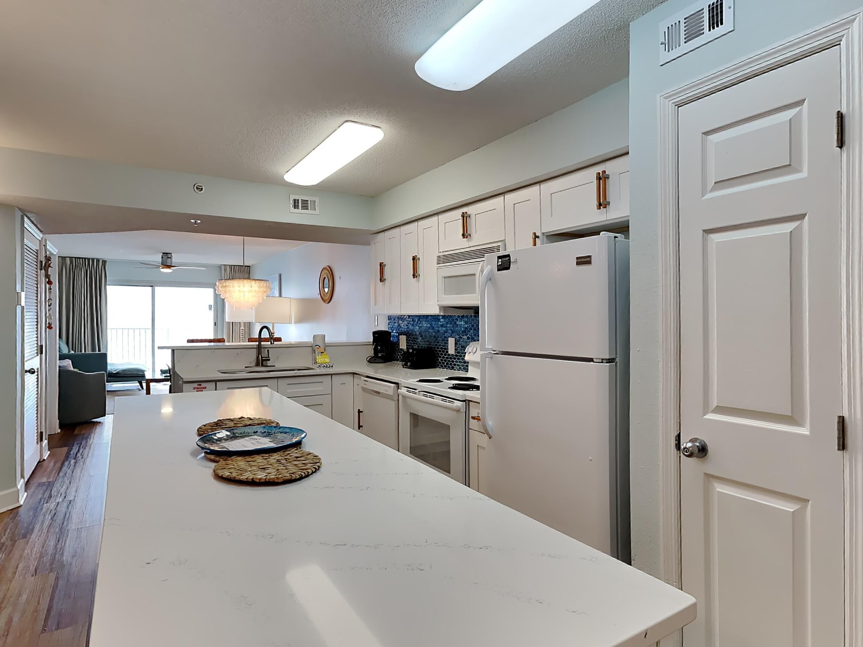 A modern kitchen with white cabinets, a built-in oven, and a refrigerator.