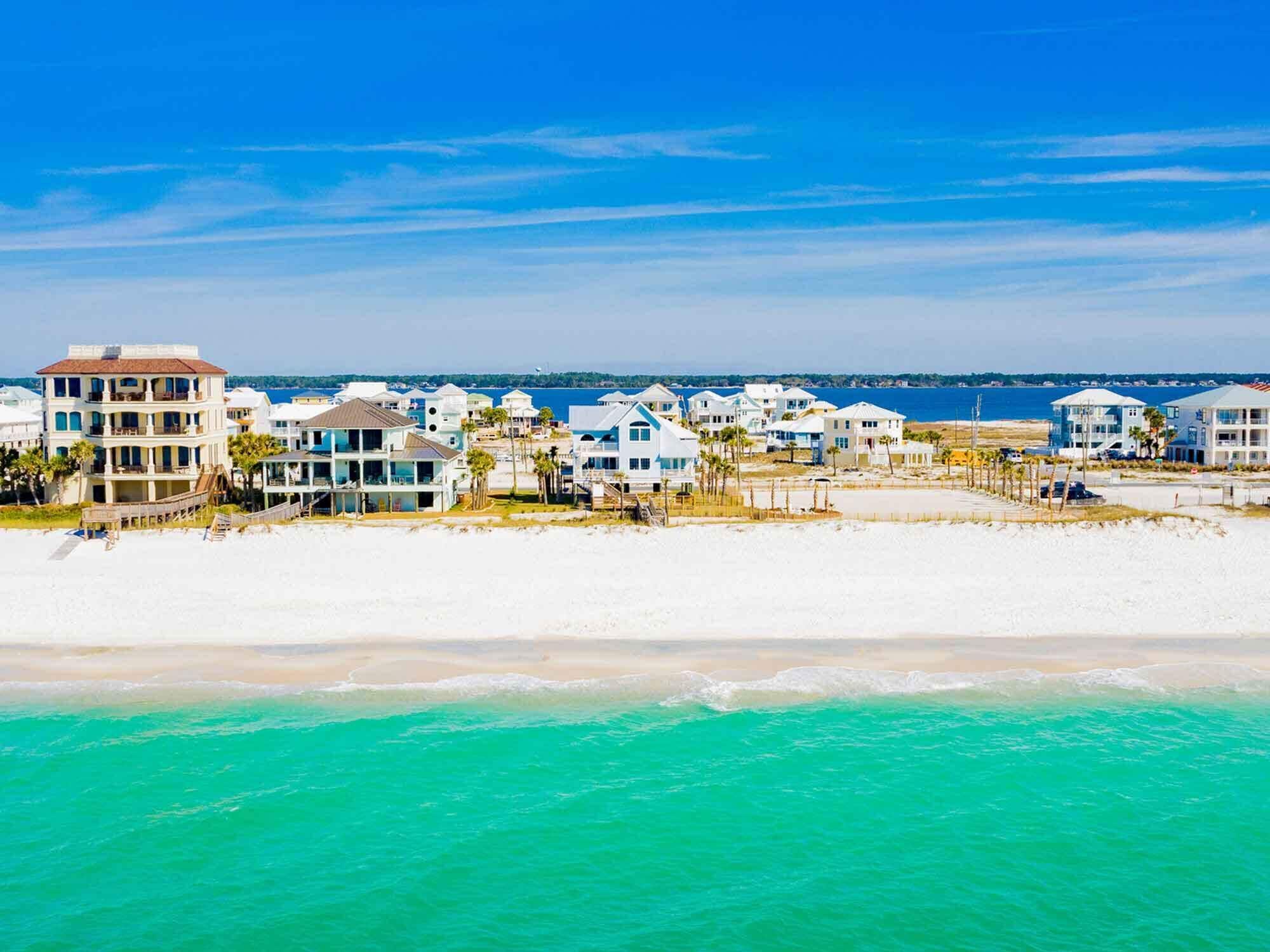 A beachfront property with multiple-story buildings, a sandy beach, and a view of the ocean.