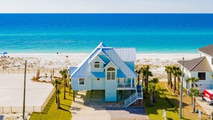 Ein Küstenhaus mit Balkon, Blick auf den Strand und blauem Himmel.
