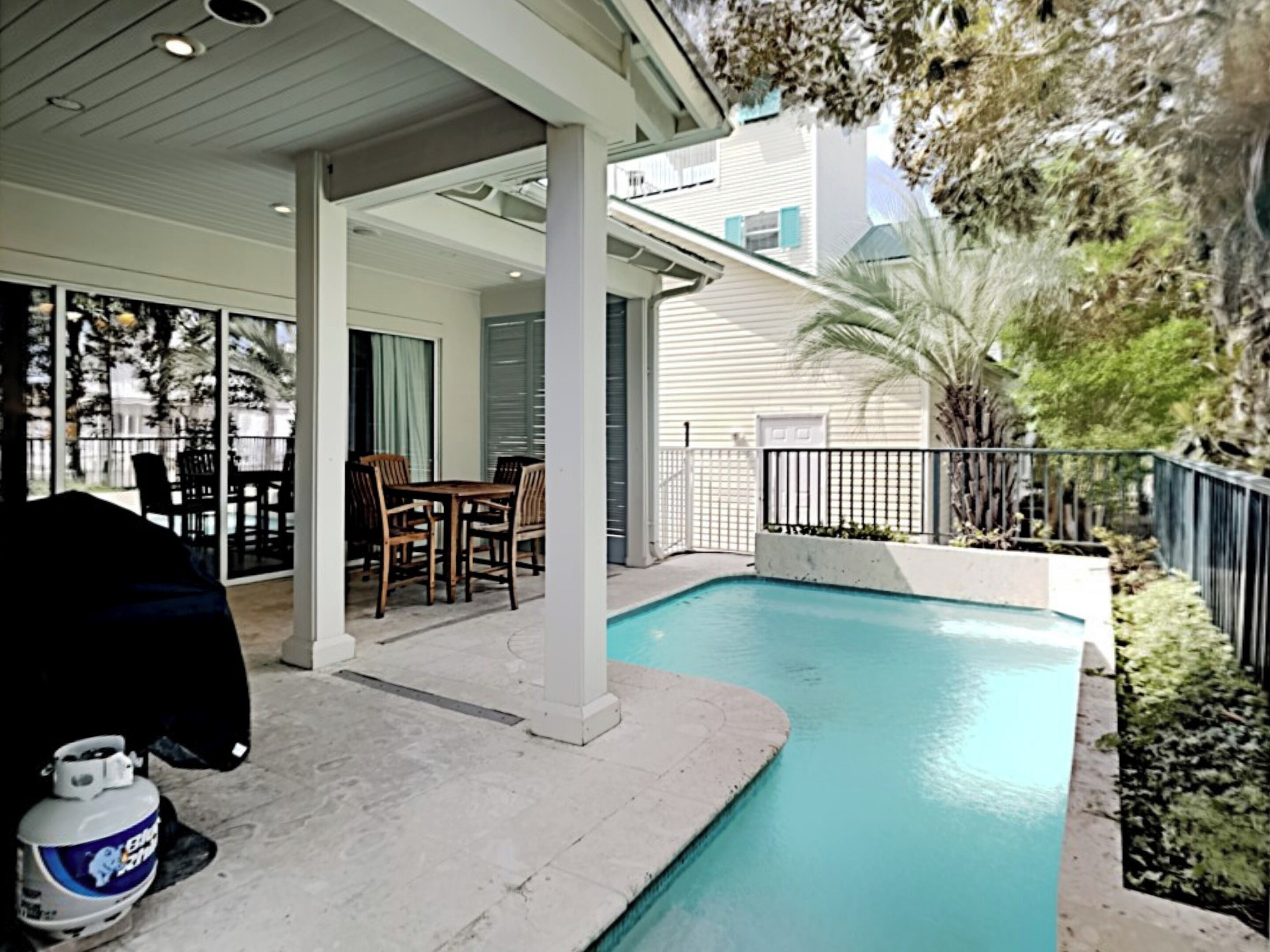A covered patio area with a pool, outdoor furniture, and a gas cylinder.