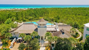 Um resort com piscina central, vários edifícios e vista para o oceano.