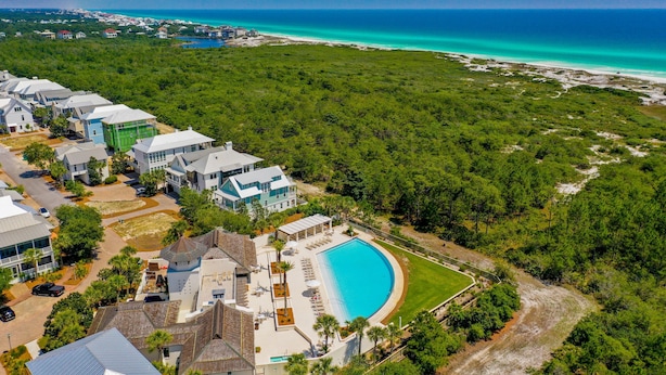 Zona residencial com uma piscina grande, cercada por vegetação exuberante e vista para o oceano.