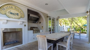 An outdoor patio with a wooden table and chairs, a grill, and a sign reading "Water Sound West Beach". - Prominence North #94A - Happy Ours by Southern Vacation Rentals (Santa Rosa Beach)