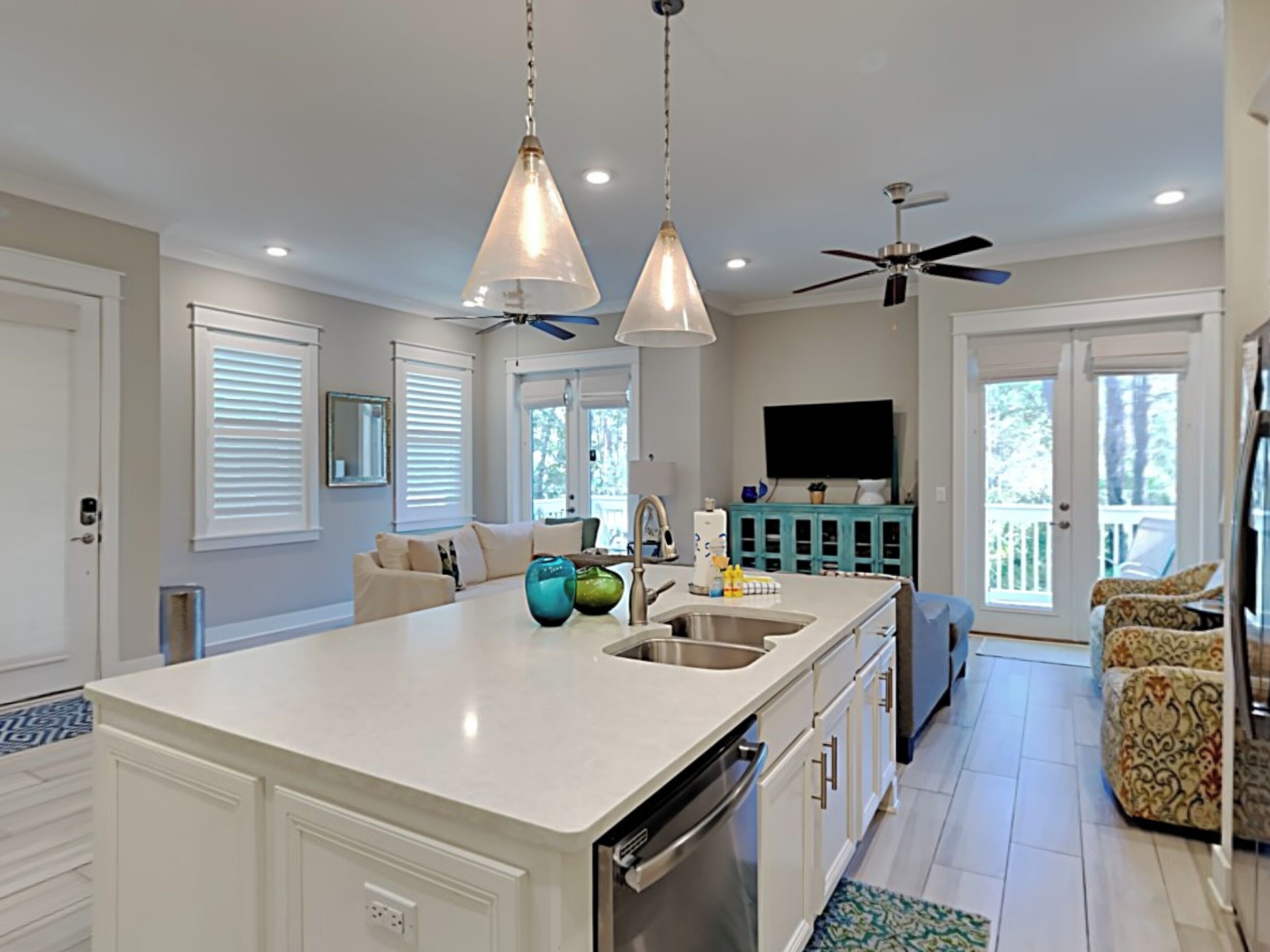 A modern kitchen with a large island, white cabinetry, and a ceiling fan.