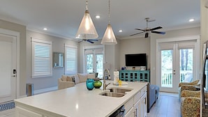 A modern kitchen with a large island, white cabinetry, and a ceiling fan. - Prominence North #94A - Happy Ours by Southern Vacation Rentals (Santa Rosa Beach)