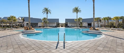 A swimming pool with a circular design, surrounded by a tiled deck and palm trees.