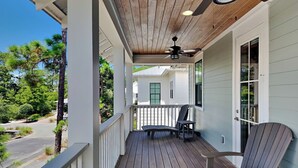 A wooden deck with a ceiling fan, a table, and two chairs. - Starfish Sanctuary by Southern Vacation Rentals (Santa Rosa Beach)