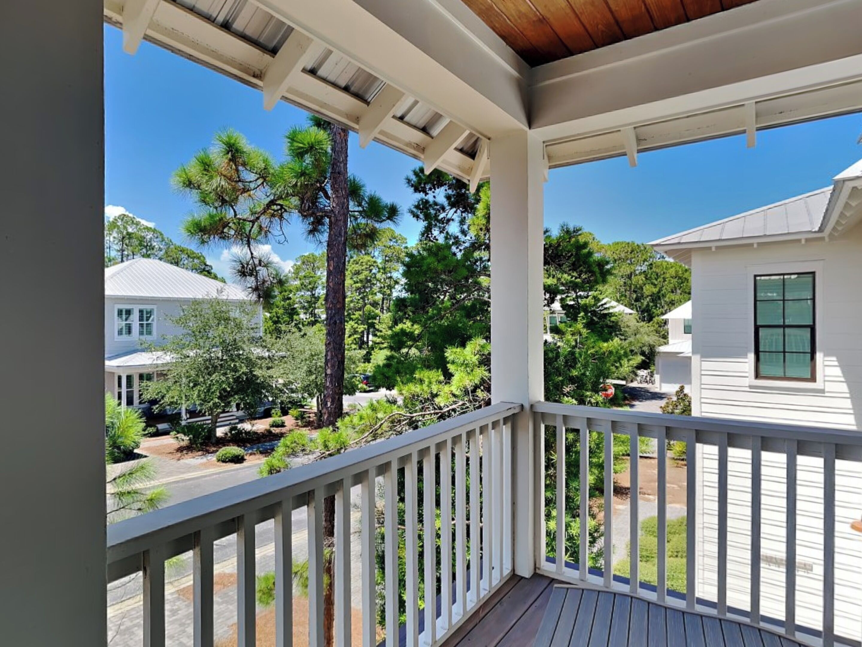 A covered porch with a view of a residential neighborhood, including houses and trees.