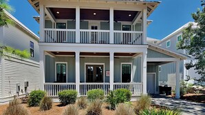 A two-story house with a balcony, a covered porch, and a well-maintained garden. - Starfish Sanctuary by Southern Vacation Rentals (Santa Rosa Beach)