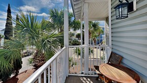 A covered outdoor area with a wooden table and chairs, surrounded by palm trees and a view of neighboring houses. - The Taj Mahal by Southern Vacation Rentals (Santa Rosa Beach)