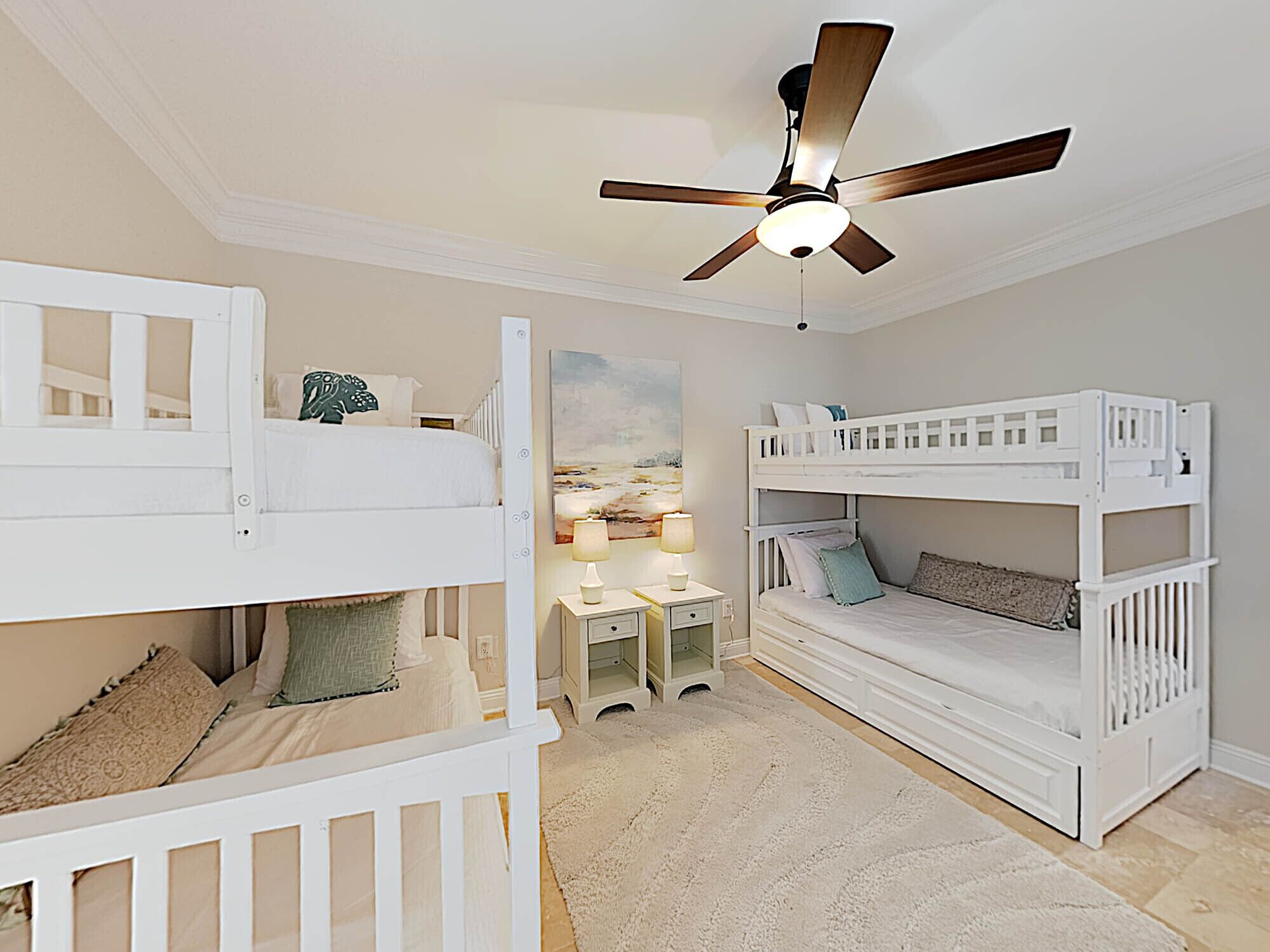 A children's bedroom with bunk beds, a desk, and a ceiling fan.