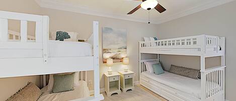 A children's bedroom with bunk beds, a desk, and a ceiling fan.