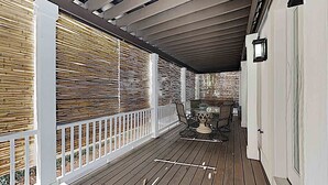 Eine überdachte Veranda mit Holzterrasse, weißer Brüstung und einem Tisch mit Stühlen.
