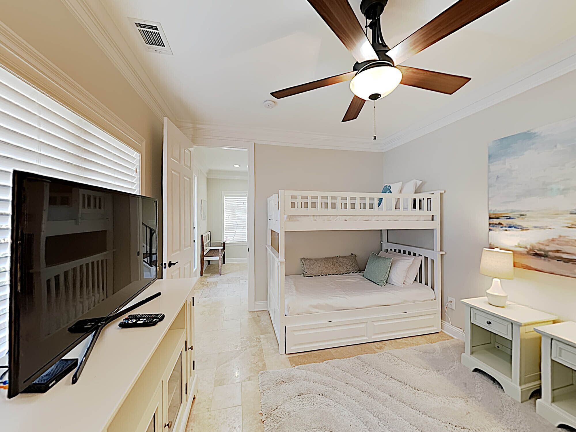 A bedroom with a bunk bed, a television, and a ceiling fan.
