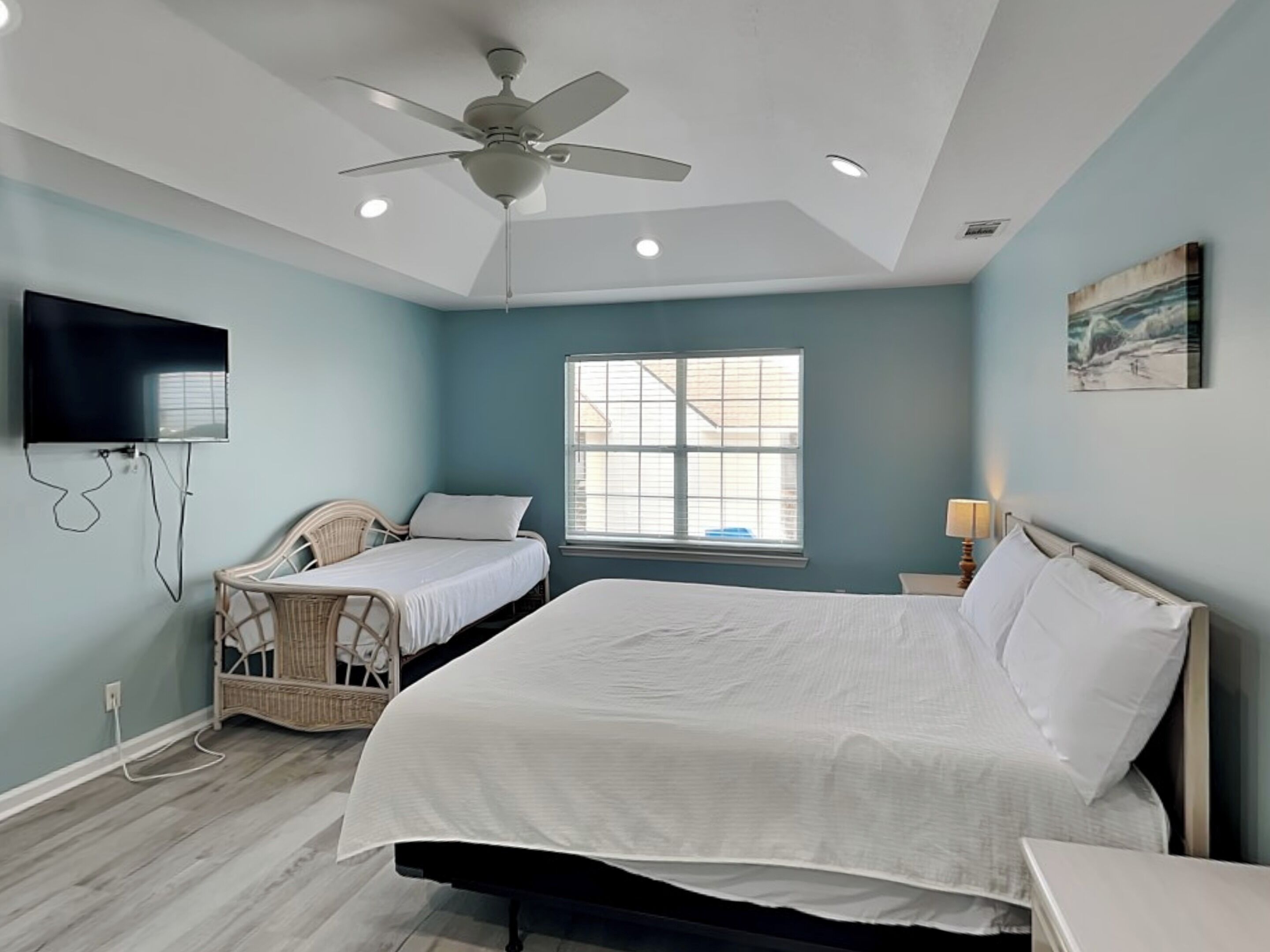 A bedroom with a bed, a chair, a television, and a ceiling fan.