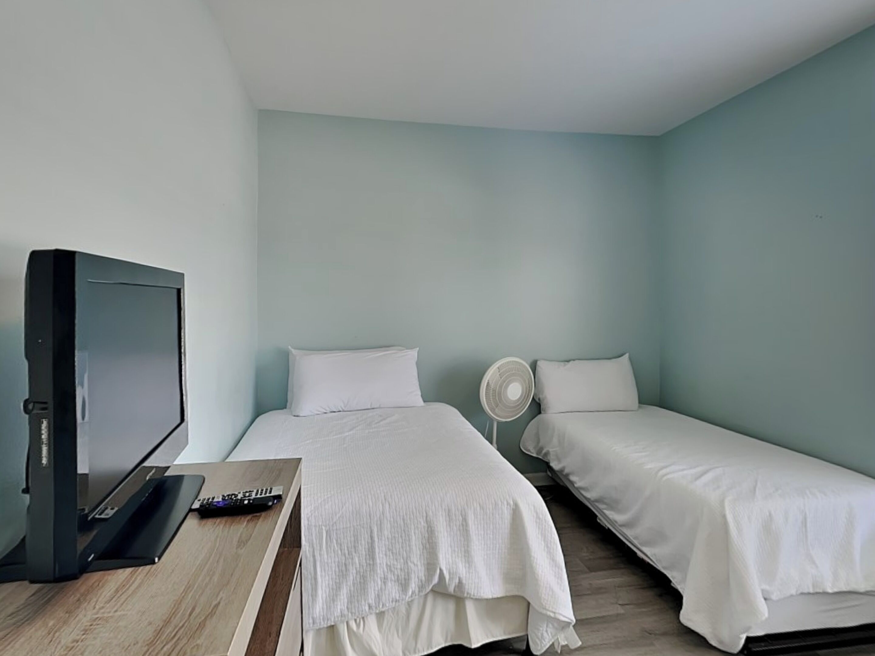 A room with a bed, a TV, and a fan.