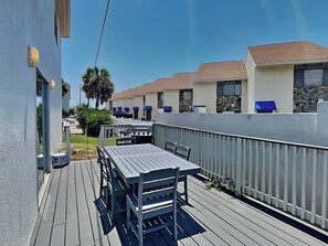 Una terraza con mesa, sillas, una parrilla y una valla blanca.