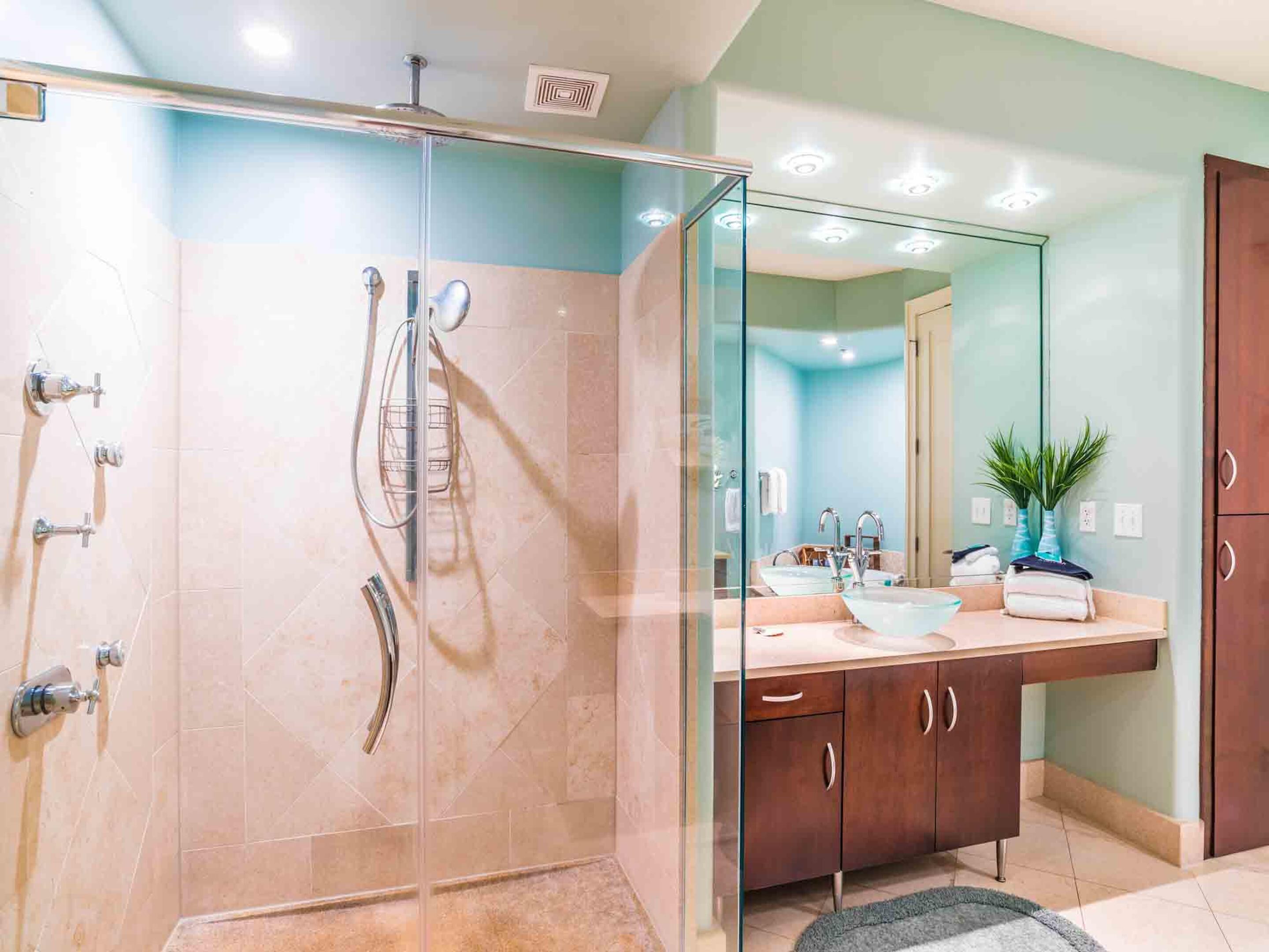 A modern bathroom with a glass shower enclosure, a vanity with a sink, and a mirror.