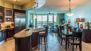 A modern kitchen with a central island, dark cabinetry, and a large window offering a view. - Bella Luna #404 by Southern Vacation Rentals (Orange Beach)