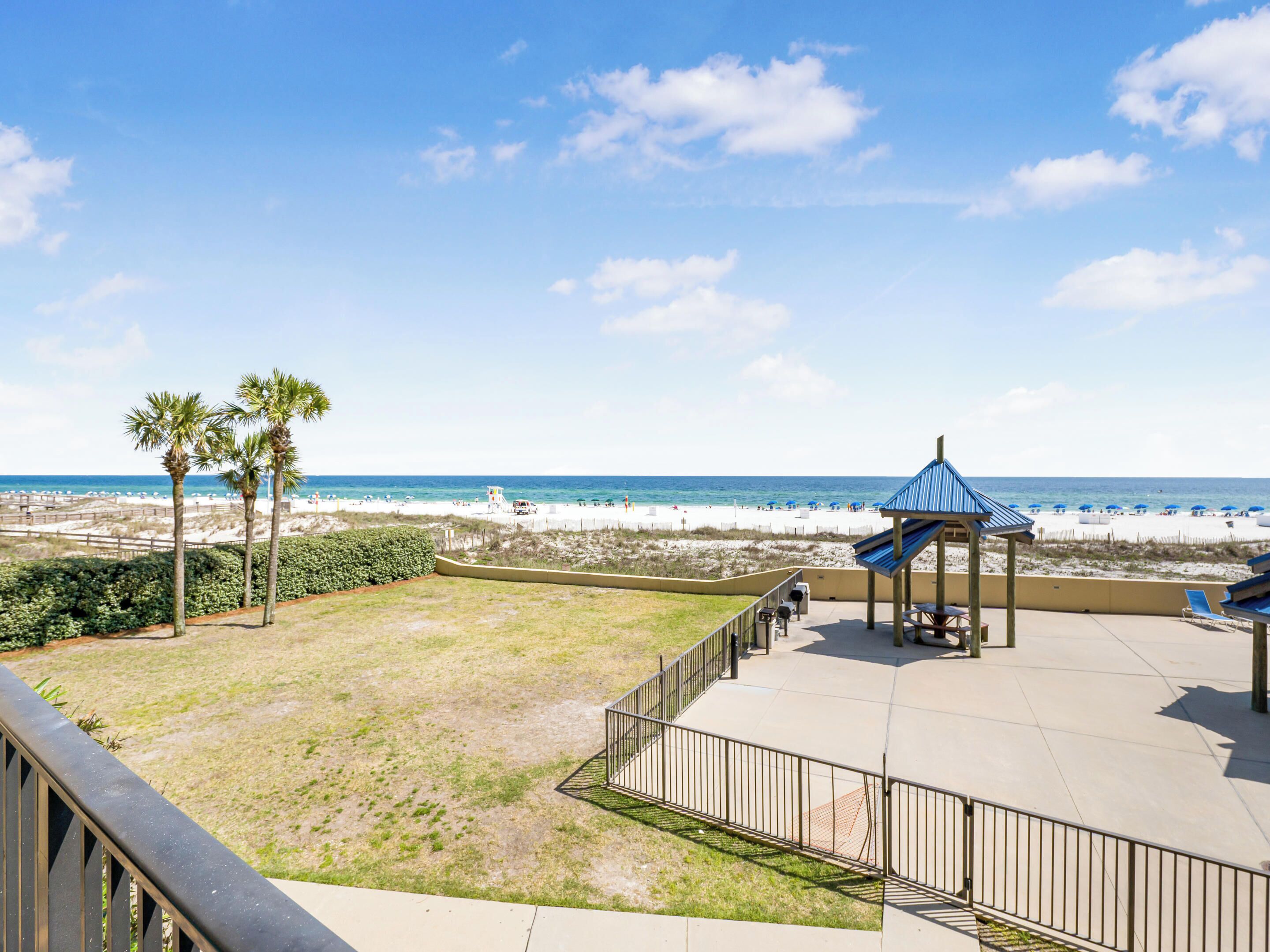 A beach view with a gazebo, palm trees, and a clear sky.