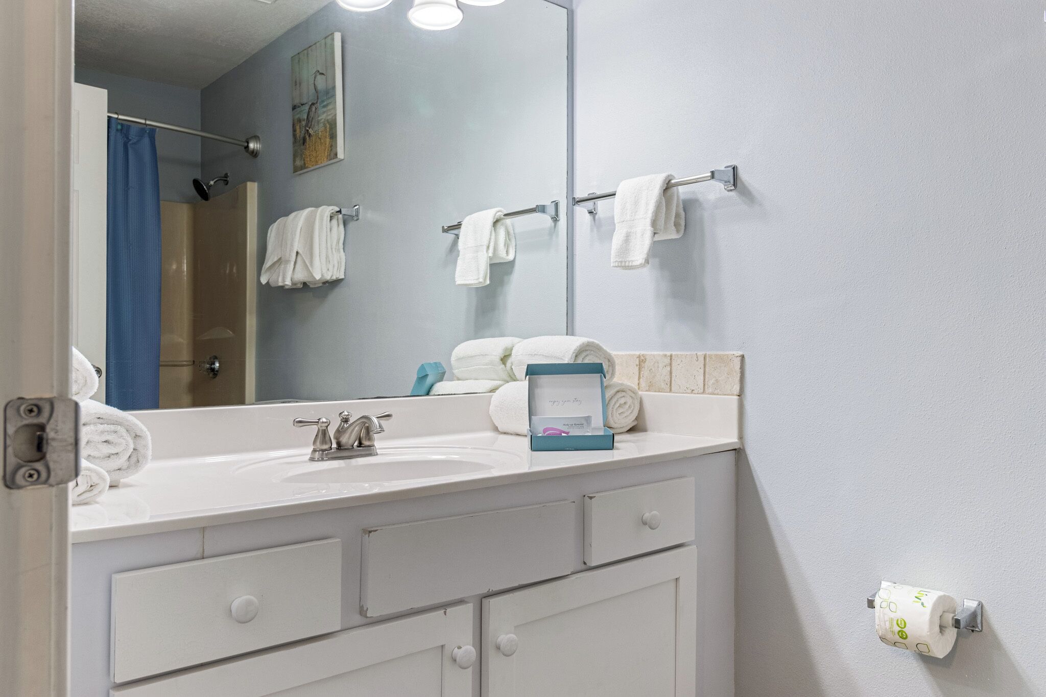 A bathroom with a white sink, a mirror, and a towel rack with multiple towels.