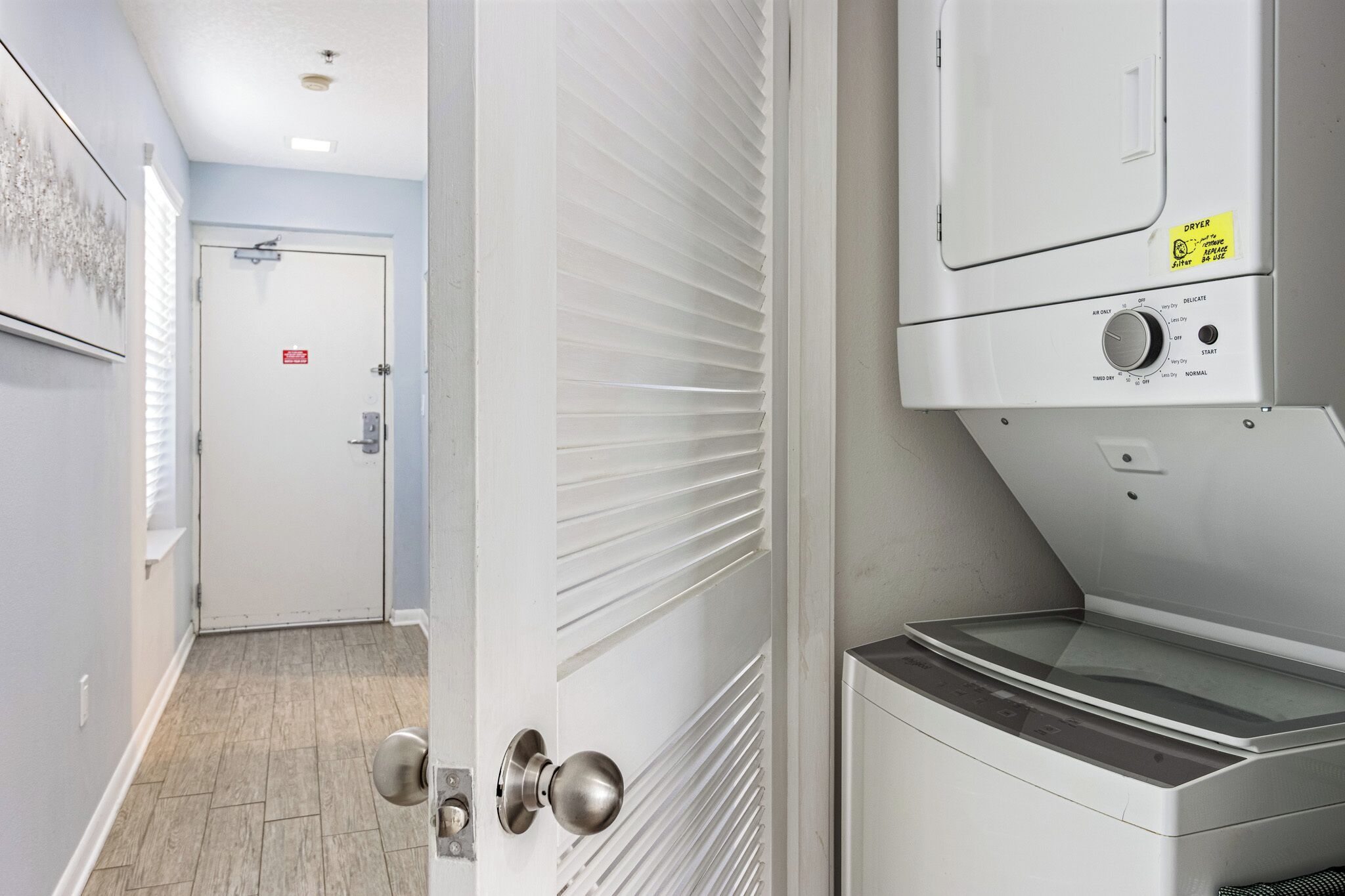 A laundry room with a dryer, a washing machine, and a door with a security lock.