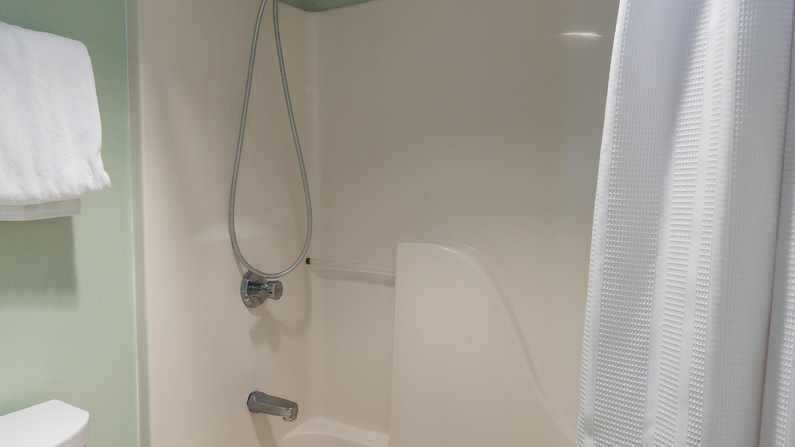 Une salle de bain avec une douche, des toilettes et une serviette accrochée au mur.