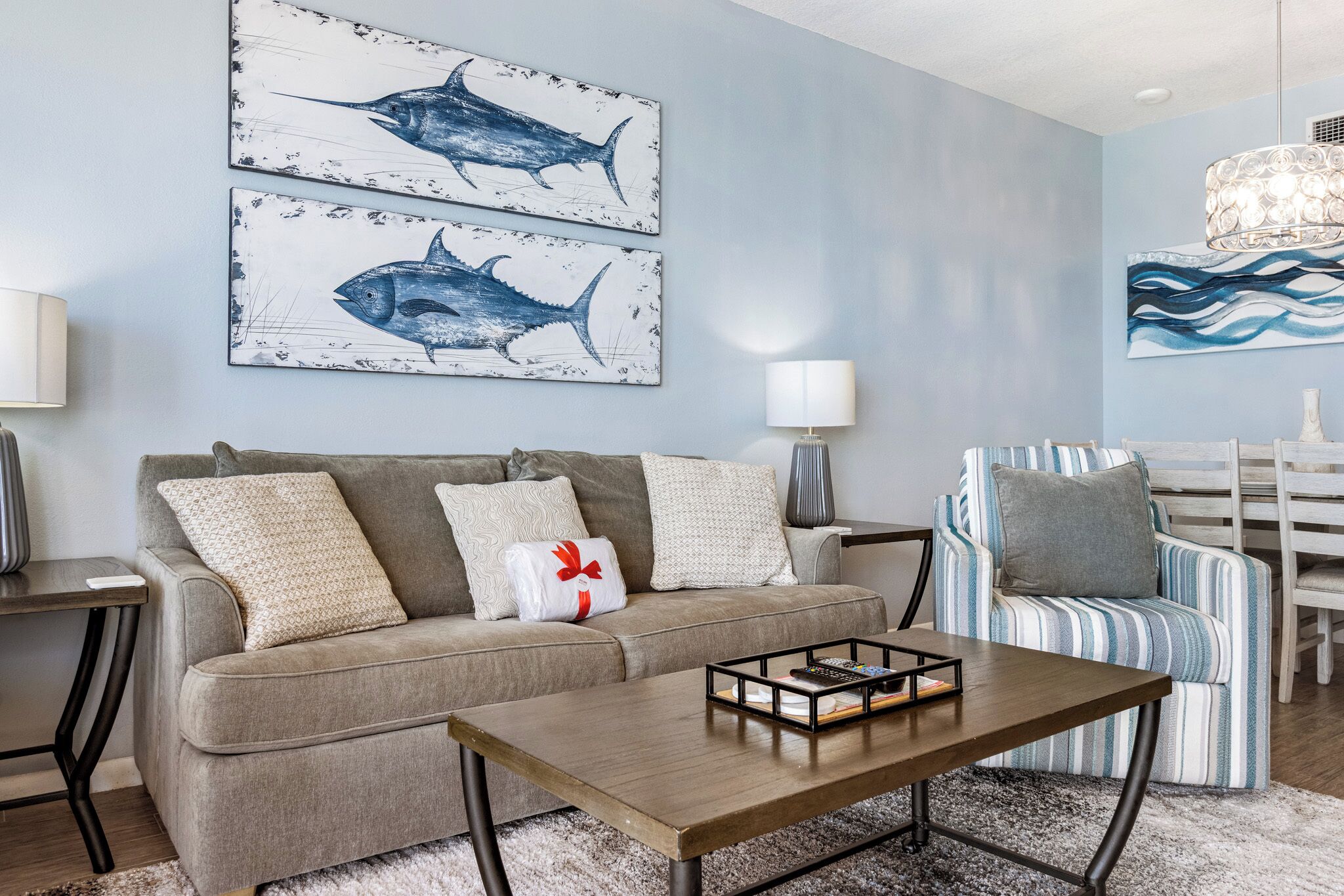 Una sala de estar con sofá, sillón, mesa de centro y una obra de arte en la pared.