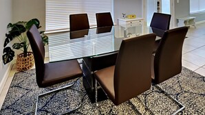 Un comedor moderno con una mesa de vidrio, sillas marrones y una planta en maceta.