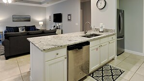 Una cocina moderna con lavavajillas integrado, un refrigerador de acero inoxidable y una isla grande con pileta.