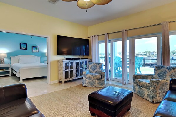 A living room with a bed, a TV, and a view of the outdoors.