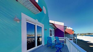 Une terrasse avec des chaises bleues et une table, donnant sur une plage.