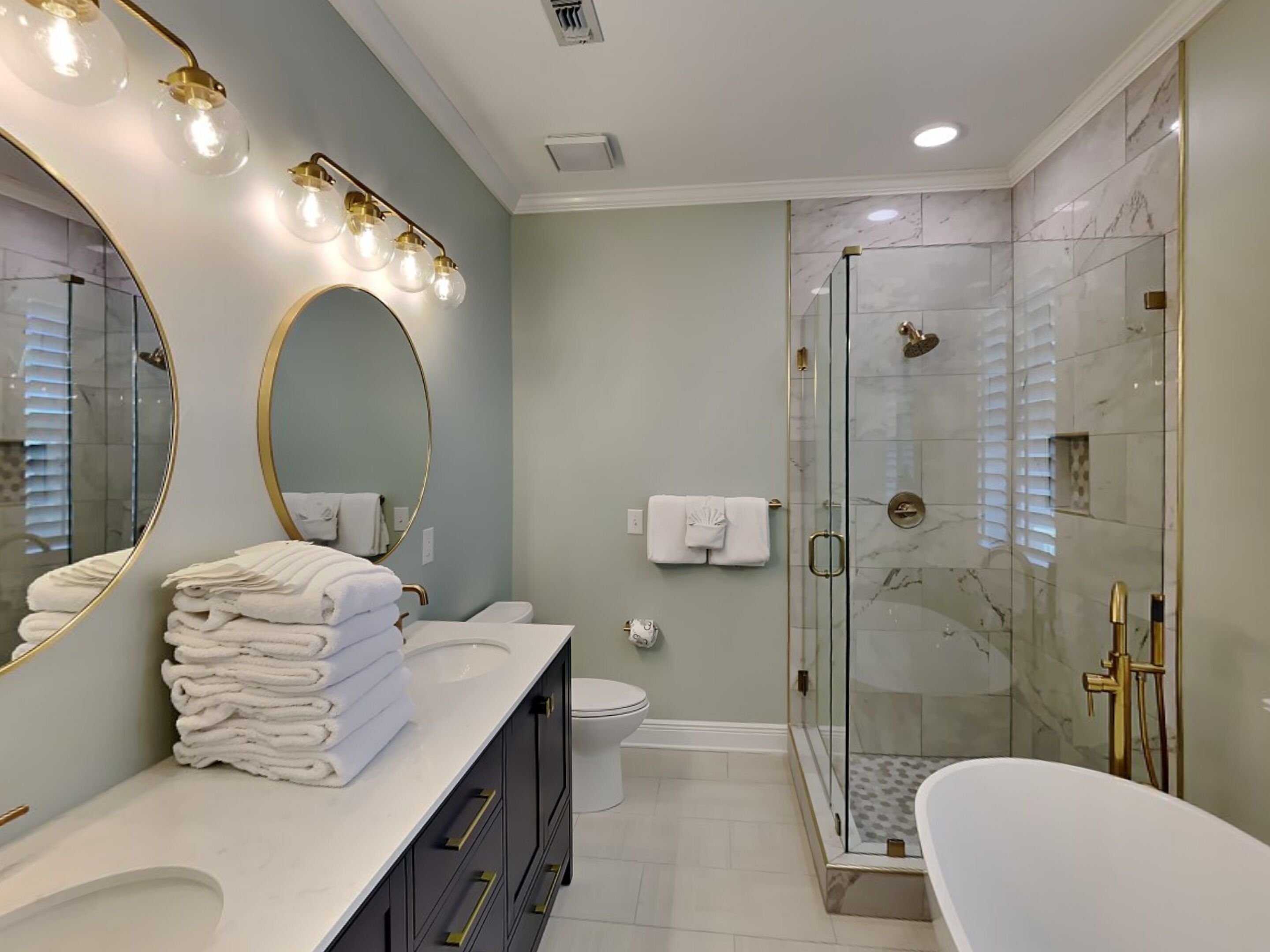 A modern bathroom with a large mirror, a bathtub, a glass-enclosed shower, and a toilet.