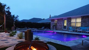 Un jardin avec une piscine, un foyer extérieur et du mobilier de jardin.