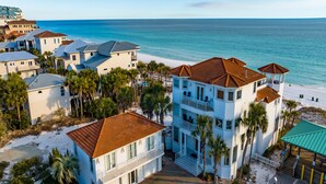 A beachfront property with multiple buildings, including a two-story house with a balcony and a covered patio area. - Already There by Southern Vacation Rentals (Destin)