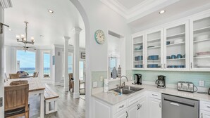 A modern kitchen with white cabinetry, a built-in dishwasher, and a view of the ocean. - Already There by Southern Vacation Rentals (Destin)