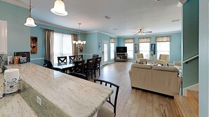 A spacious living area with a dining table, sofas, and a TV. - Ocean Breeze by Southern Vacation Rentals (Destin)