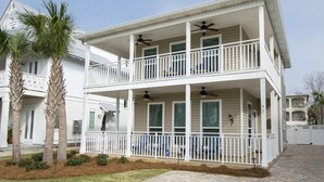 A two-story house with a balcony, a covered porch, and a fenced yard. - Ocean Breeze by Southern Vacation Rentals (Destin)